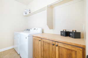 Laundry room featuring washing machine and clothes dryer, light tile patterned flooring, and cabinet space