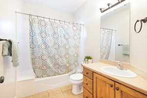 Full bathroom featuring shower / bath combination with curtain, vanity, and light tile patterned floors