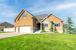 View of front of house with stone siding, stucco siding, concrete driveway, and an attached garage