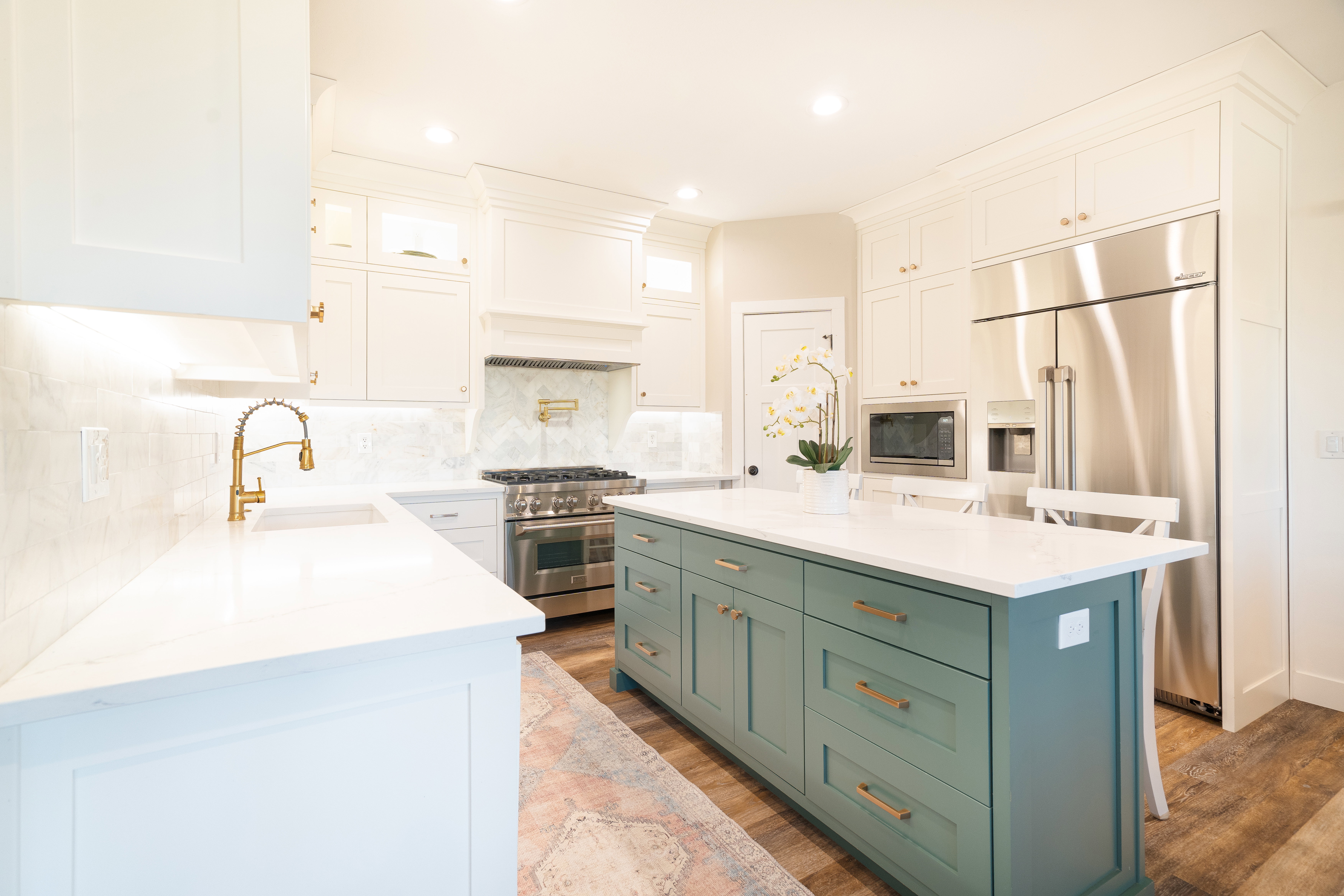 Two tone kitchen featuring two tone cabinets, a center island, high end appliances, light stone countertops, and light wood finished floors
