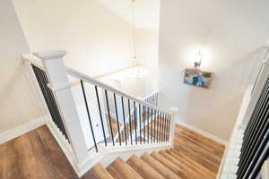 Stairway with wood finished floors, a high ceiling, and hanging lights