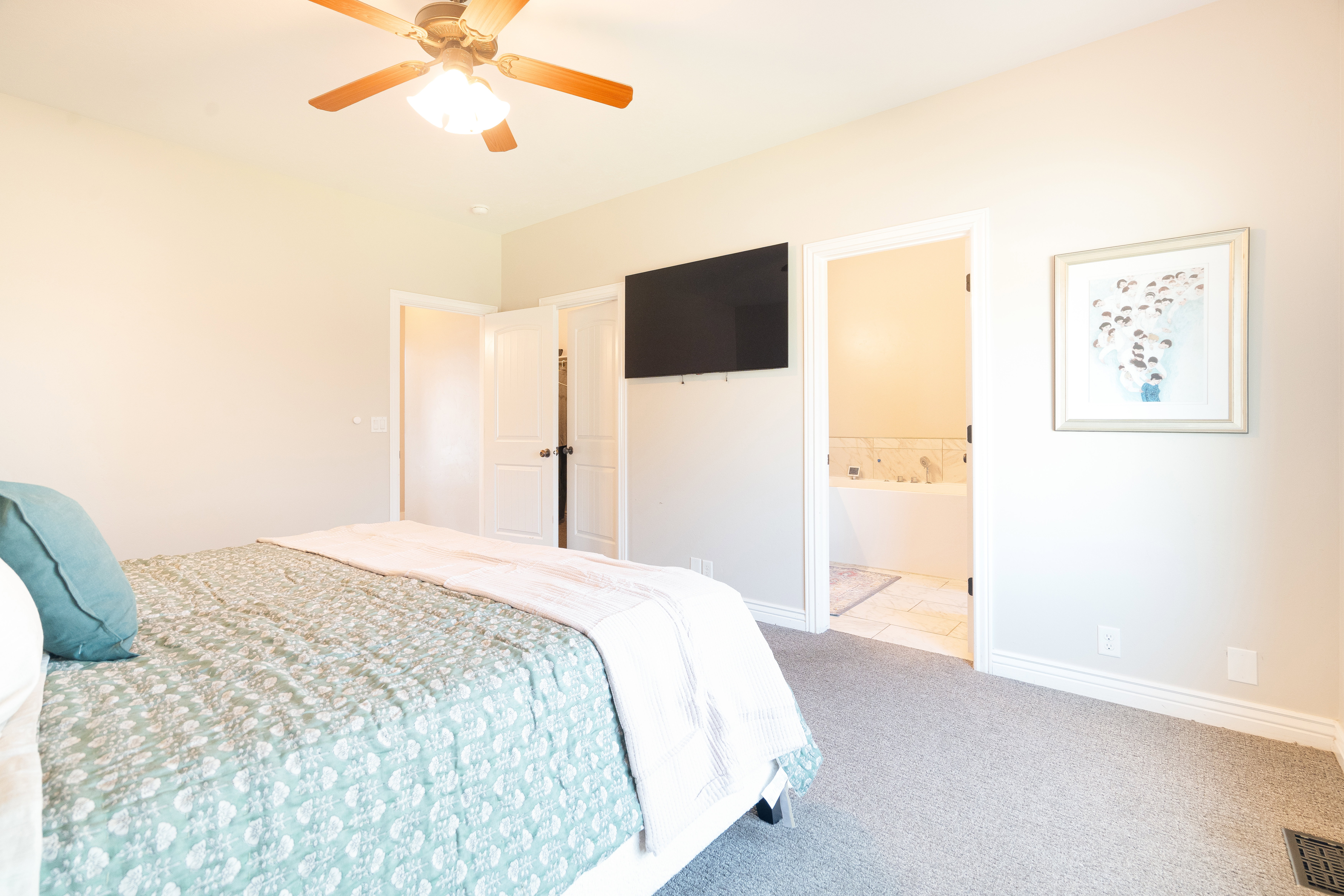 Carpeted bedroom with a ceiling fan and connected bathroom