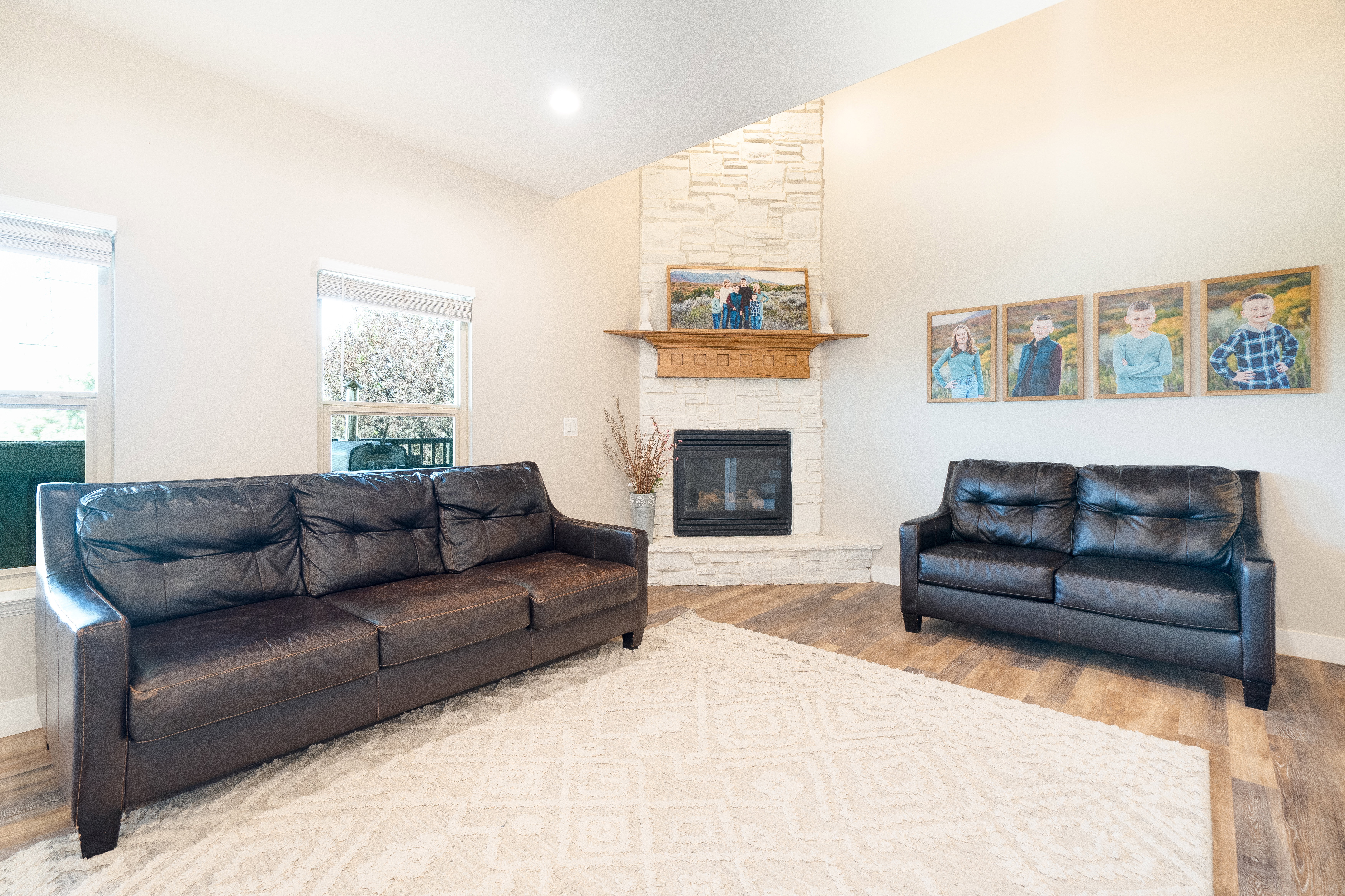 Living area featuring vaulted ceiling, light wood finished floors, a fireplace, and recessed lighting