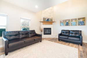 Living area featuring vaulted ceiling, light wood finished floors, a fireplace, and recessed lighting