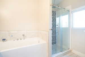 Bathroom featuring a stall shower, a bath, and marble look tiles