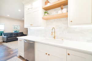 Kitchen with white cabinets, dishwasher, backsplash, open shelves, and recessed lighting