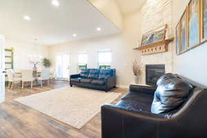 Living area featuring a stone fireplace, light wood-type flooring, and hanging lights