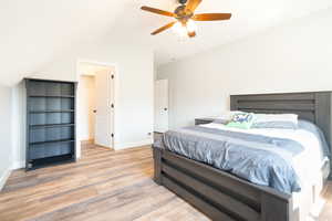 Bedroom featuring light wood-style floors, a ceiling fan, and lofted ceiling