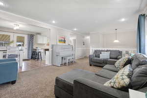 Living area with light carpet, recessed lighting, and ornamental molding