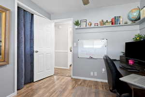 Home office with light wood-style flooring and a ceiling fan