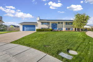Bi-level home featuring solar panels, driveway, a chimney, and brick siding