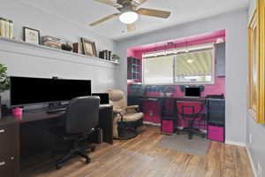 Office space featuring ceiling fan, light wood-style floors, a textured ceiling, and built in desk
