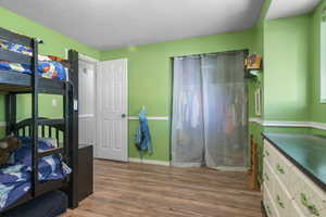 Bedroom with wood finished floors and a textured ceiling