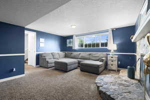 Living area featuring carpet flooring, a textured ceiling, and a fireplace
