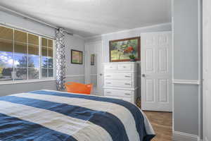 Bedroom with dark wood-style flooring and a textured ceiling
