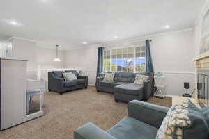 Living area featuring crown molding, carpet floors, a glass covered fireplace, and recessed lighting