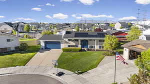 View of front facade featuring concrete driveway, solar panels, a residential view, an attached garage, and a front yard