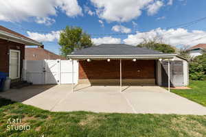 View of patio featuring a gate and a storage unit