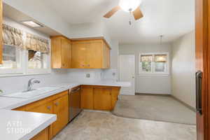 Kitchen featuring light countertops, stainless steel dishwasher, a ceiling fan, and decorative light fixtures