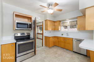 Kitchen featuring stainless steel appliances, light countertops, a ceiling fan, and wood finish cabinets