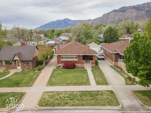 View of front of home featuring brick siding, a residential view, a mountain view, driveway, and a chimney