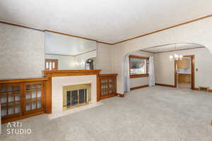 Unfurnished living room with arched walkways, light colored carpet, ornamental molding, and a tile fireplace with built ins.