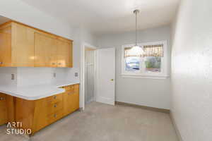 Kitchen featuring light countertops, pendant lighting, and light wood finish cabinets