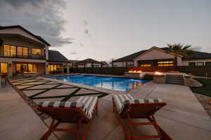 Pool at dusk featuring a patio, a fenced backyard, and a balcony