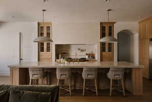 Kitchen with a breakfast bar area, glass insert cabinets, dark wood finished floors, and recessed lighting