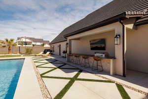 View of swimming pool featuring patio surround and outdoor kitchen