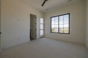 Unfurnished room featuring light colored carpet and a ceiling fan En suite
