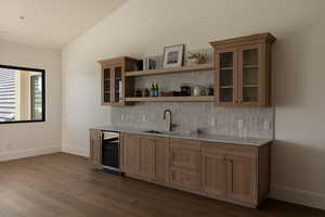 Indoor wet bar with glass fronted cabinets, backsplash, lofted ceiling, wine cooler, and light stone counters