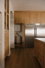 Kitchen with stainless steel built in fridge, dark wood-style flooring, wood finish cabinetry, and arched walkways
