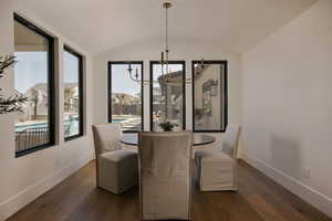 Dining space featuring suspended lighting, wood-type flooring, a barrel ceiling, and healthy amount of natural light