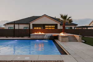 View of pool featuring a fire pit, patio surround, and a fenced backyard