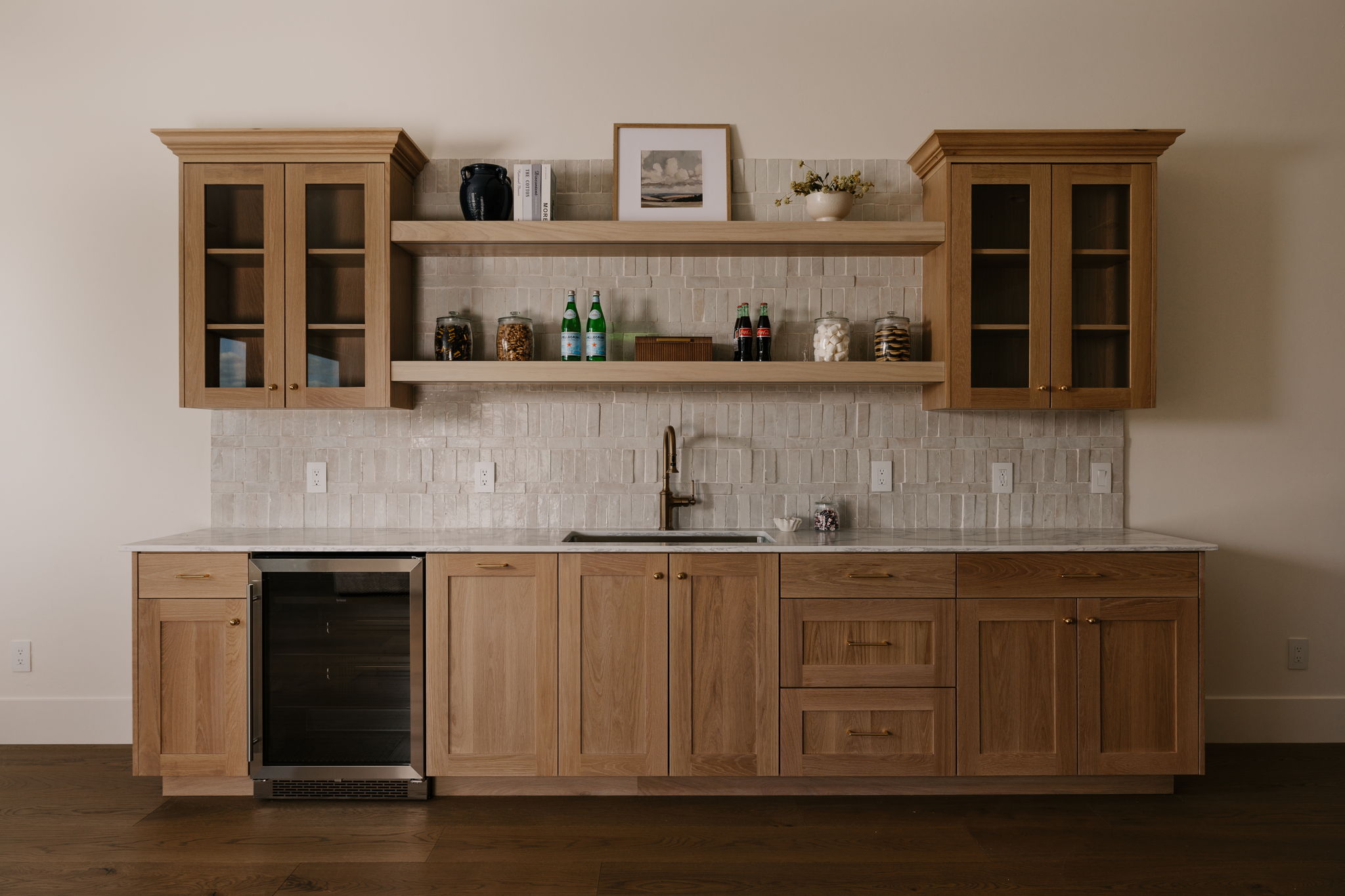 Indoor wet bar featuring glass fronted cabinets, beverage cooler, tasteful backsplash, and light stone counters