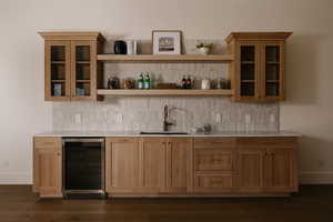 Indoor wet bar featuring glass fronted cabinets, beverage cooler, tasteful backsplash, and light stone counters
