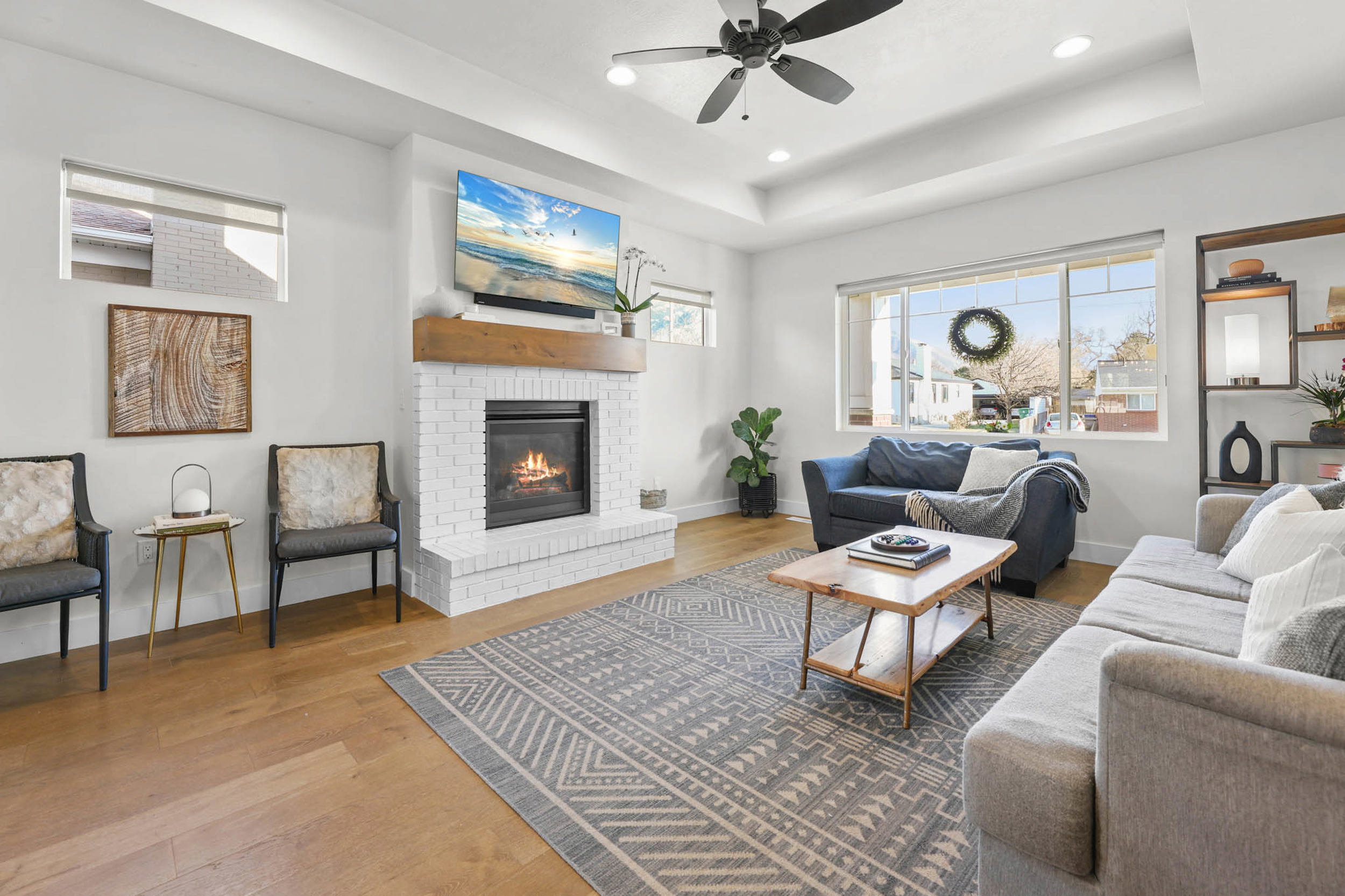 Living room with recessed lighting, a fireplace, wood finished floors, ceiling fan, and a raised ceiling