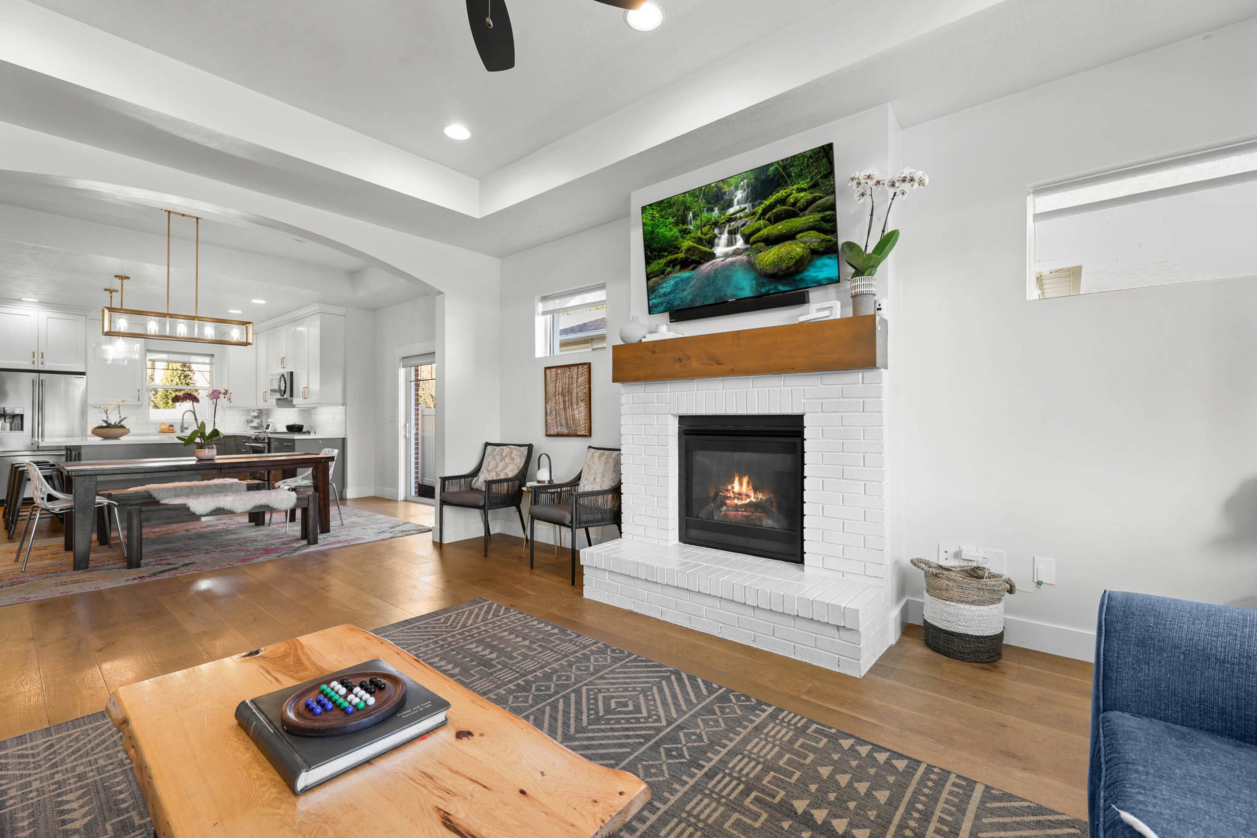 Living room featuring hardwood / wood-style floors, a tray ceiling, arched walkways, a ceiling fan, and a fireplace