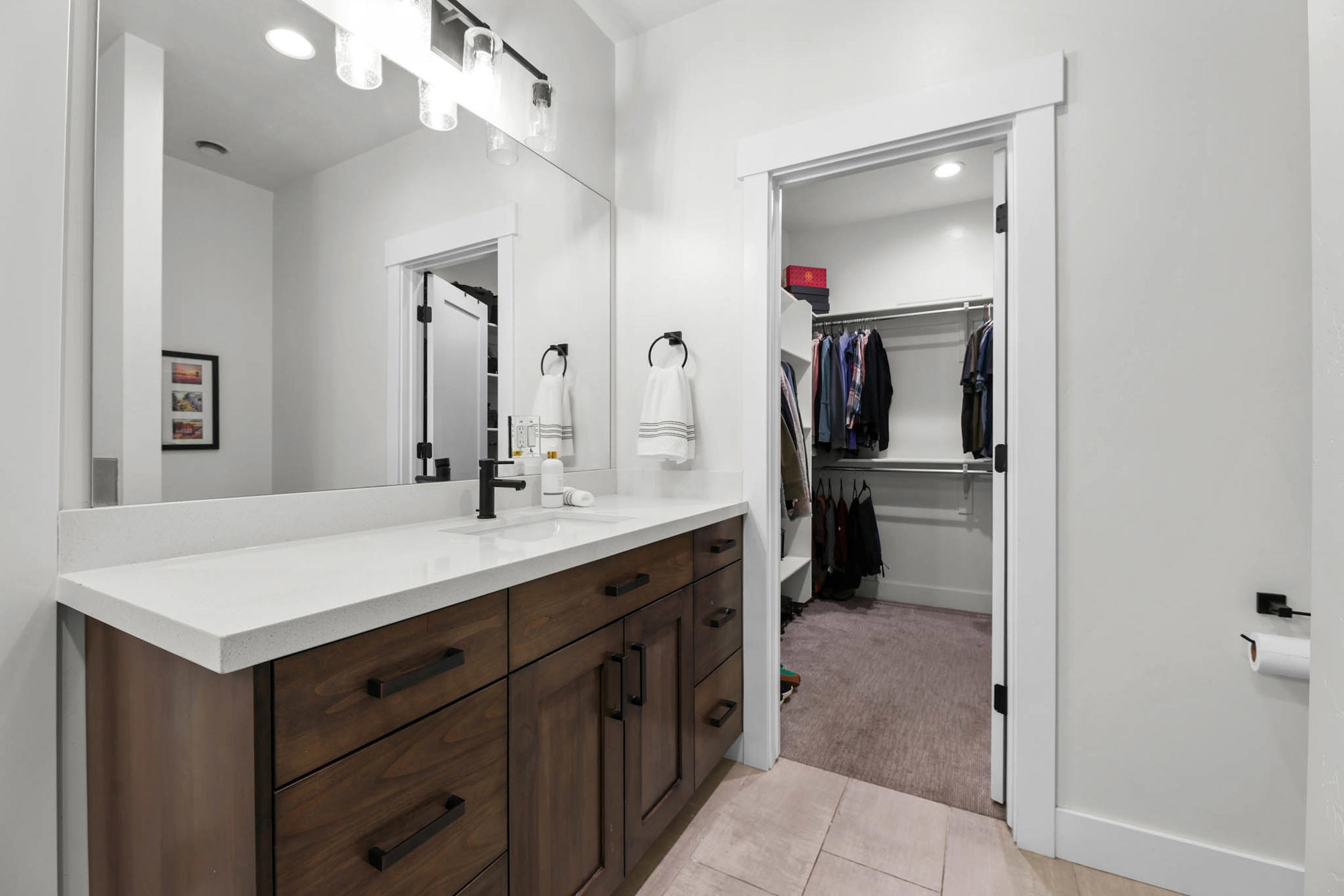Full bathroom featuring vanity, a walk in closet, light tile patterned floors, light colored carpet, and recessed lighting