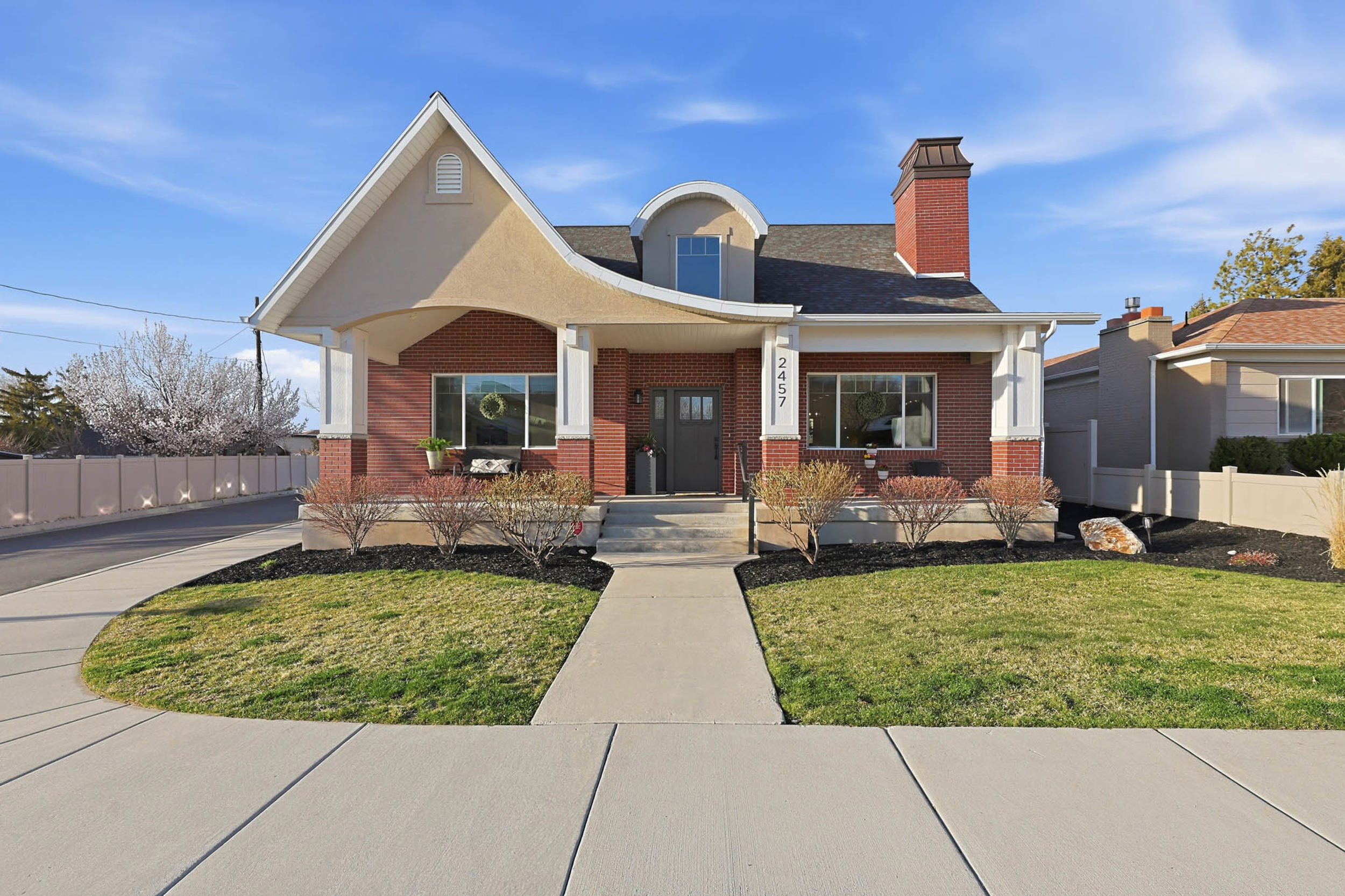 View of front of property featuring covered porch, brick siding, and a chimney