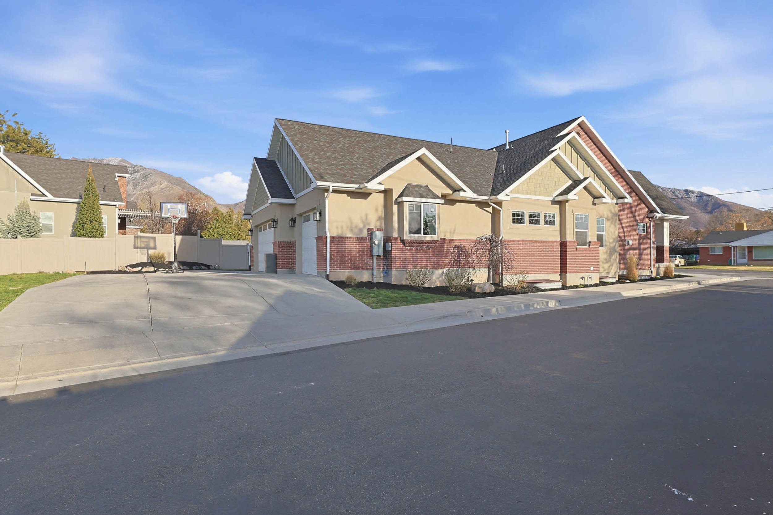 View of front of property featuring a mountain view, brick siding, a garage, a residential view, and concrete driveway