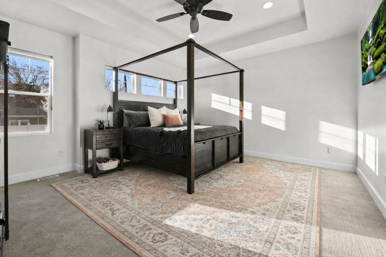 Bedroom with light colored carpet, ceiling fan, a raised ceiling, and recessed lighting