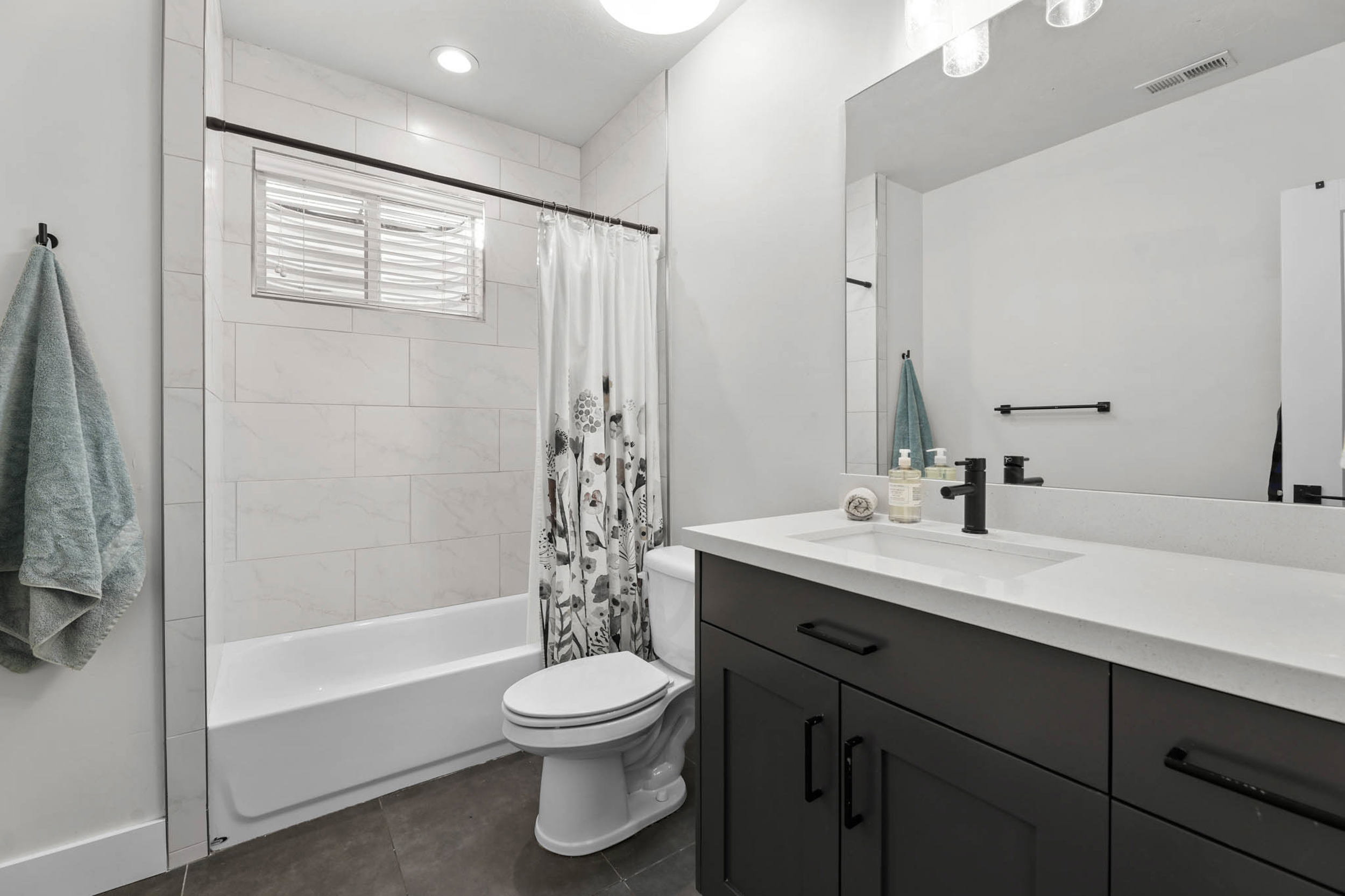 Bathroom featuring vanity, shower / tub combo with curtain, and dark tile patterned floors