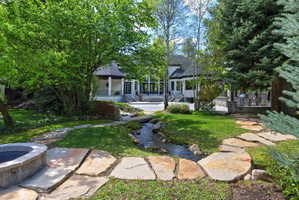 Back of house featuring a garden pond, a patio, meandering paths and fire pit