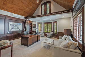 Library/Office with a vaulted wooden panel ceiling, wainscoting, custom wood built ins, and a charming loft with ladder, plantation shutters.