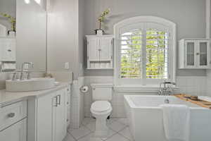 Bathroom with vanity, wainscoting, a soaking tub, light tile patterned flooring, tile walls, and glass shower