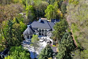 Aerial view of property and surrounding area featuring a tree filled landscape