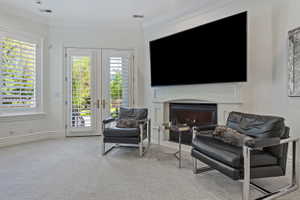 Living area featuring french doors, light colored carpet, crown molding, and a gas fireplace