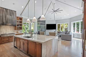 A true bespoke Kitchen with light stone countertops, a center island with sink, wood finish cabinetry, light wood-style floors, brushed metal gas fireplace and lovely family gathering room, plus dining cove.